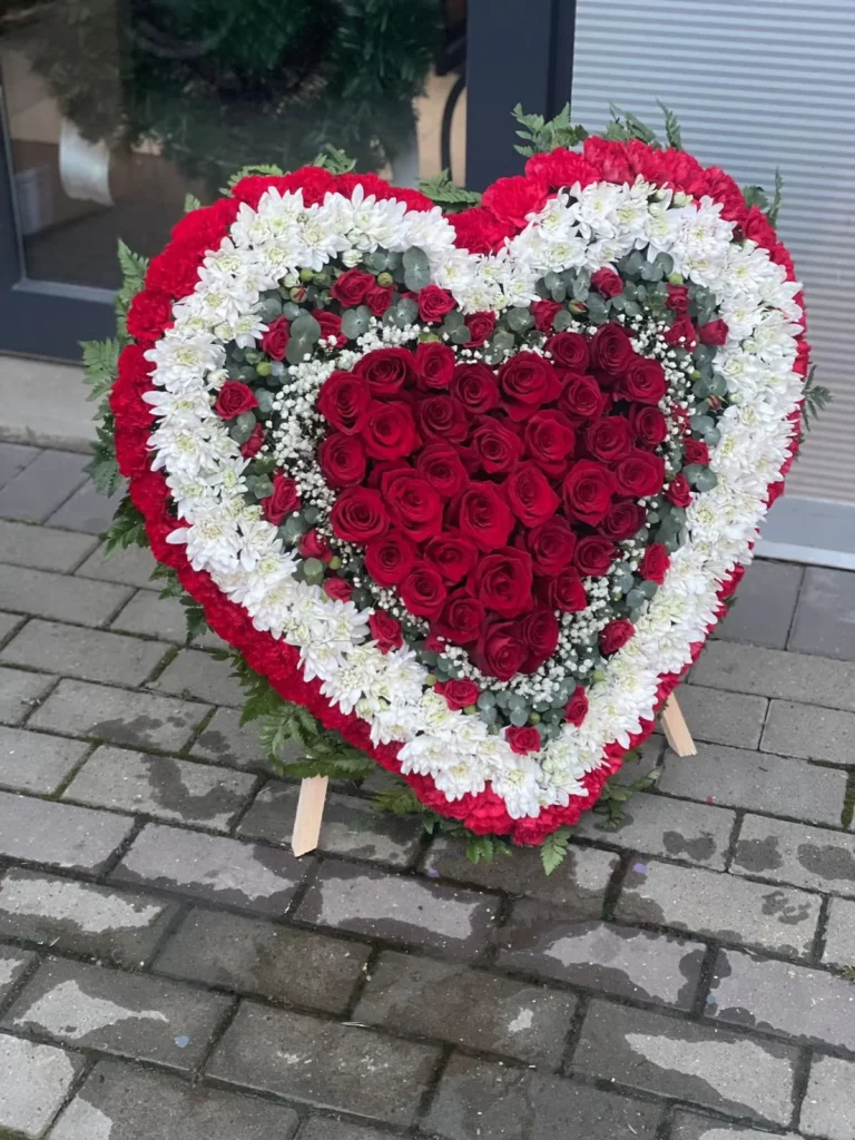 Aranjament funerar în formă de inimă din trandafiri roșii, crizanteme albe și garoafe