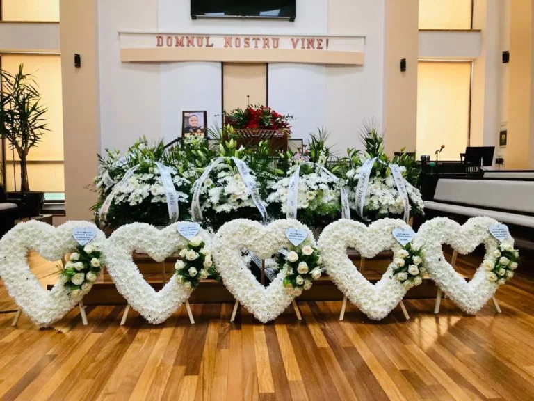 Coroane funerare în formă de inimă din crizanteme albe cu trandafiri, în capelă