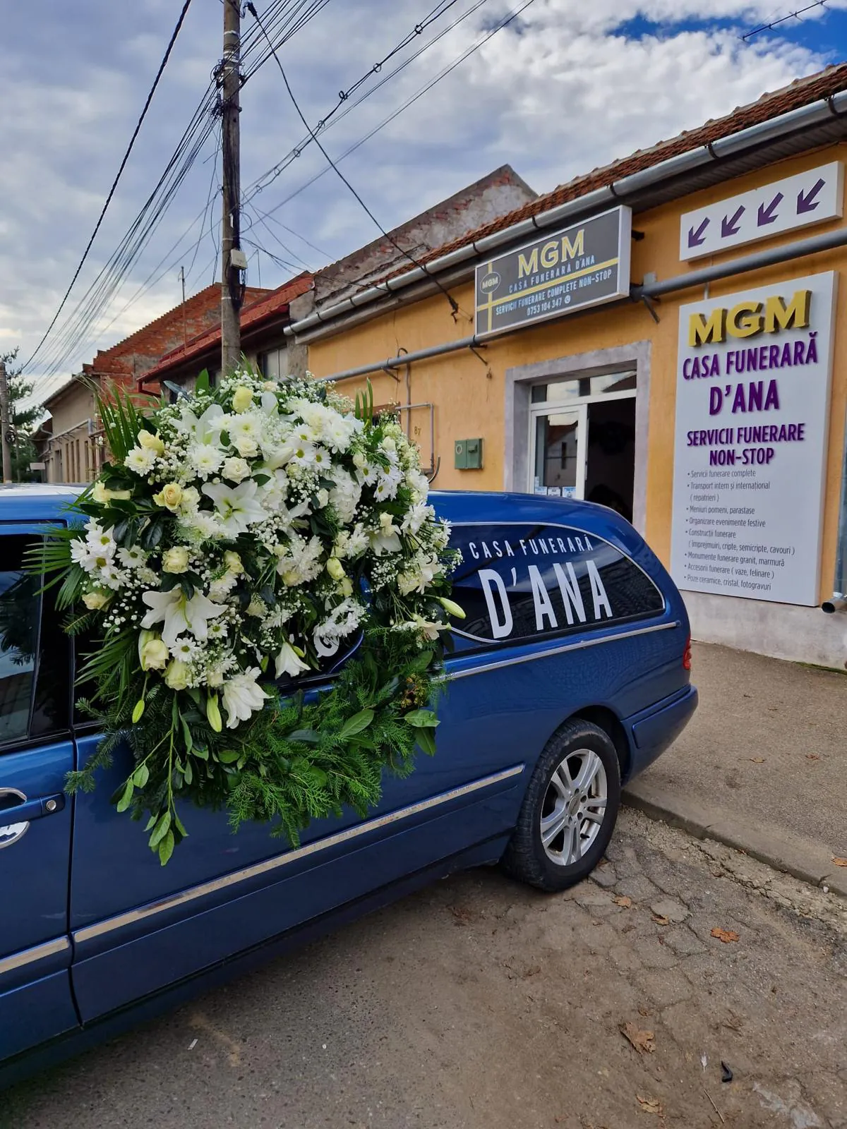 Autospeciala funerară MGM Casa Funerară D'Ana cu coroană albă, în fața sediului din Lugoj